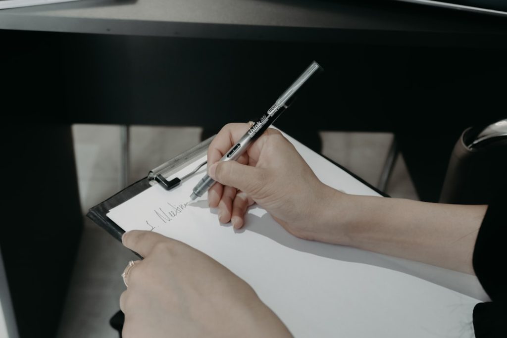 Person writing on a clipboard with a pen.